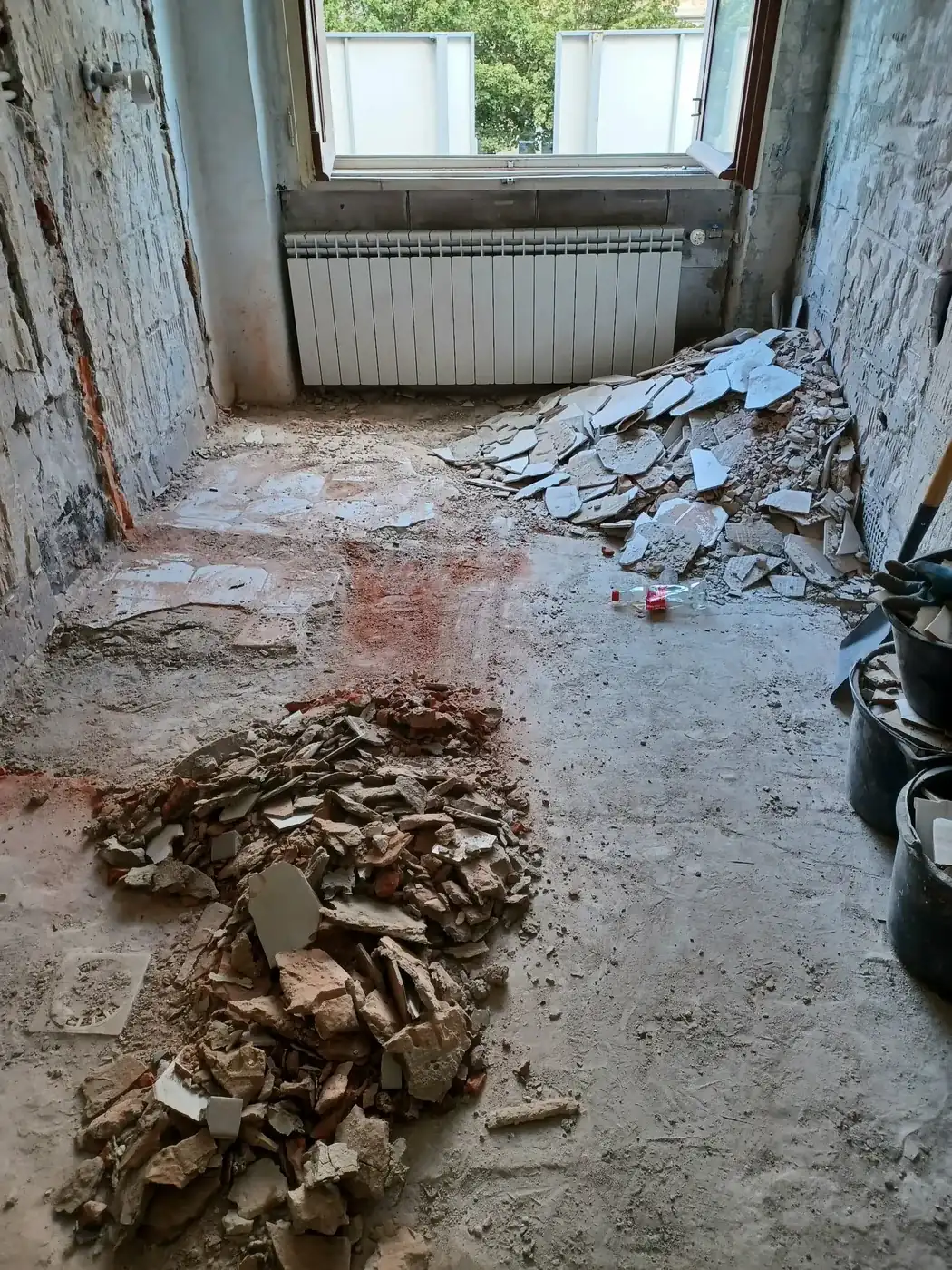 Sterty skutych płytek i gruzu na podłodze pomieszczenia przygotowanego do wywozu