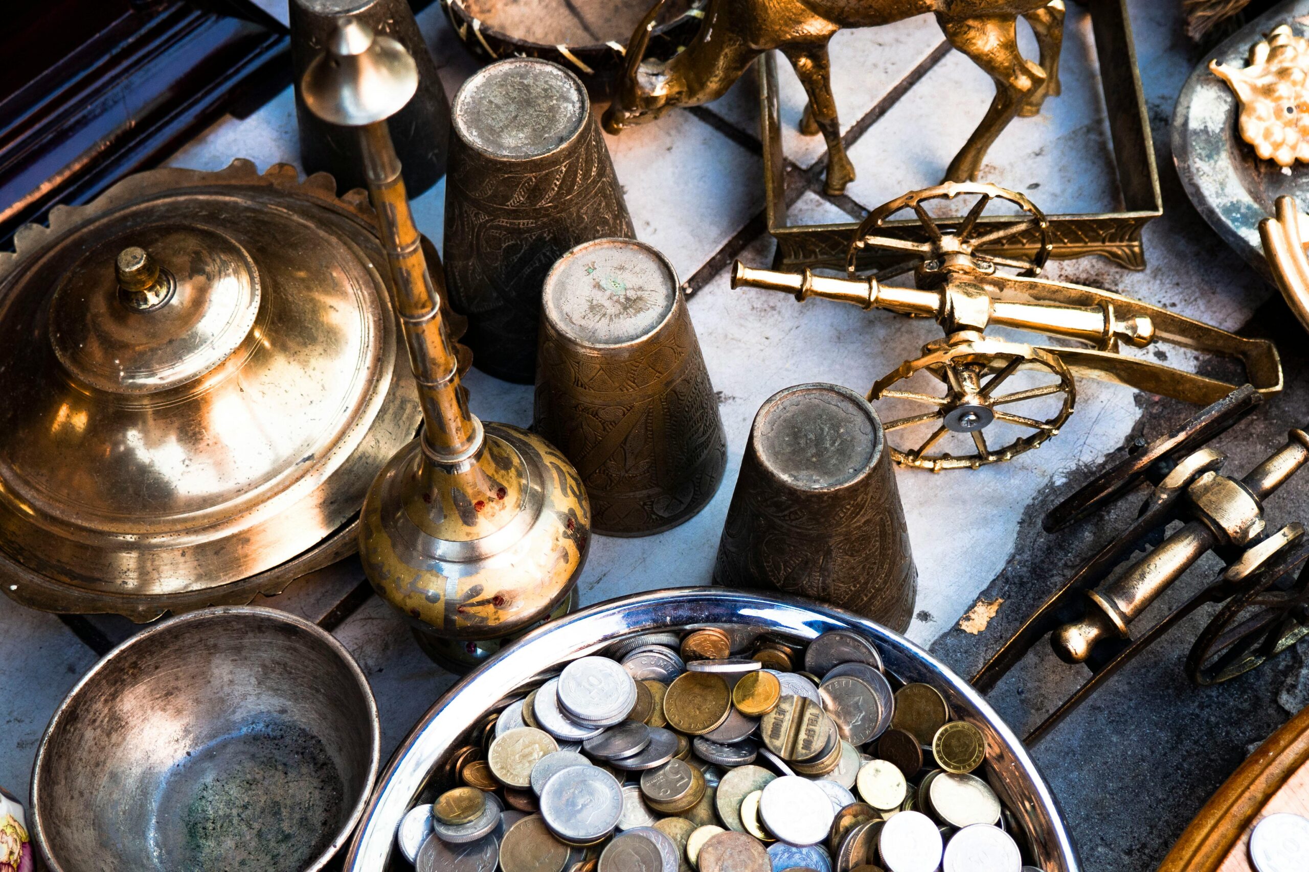A collection of vintage brass items and coins arranged in a still life composition, showcasing historical artifacts.