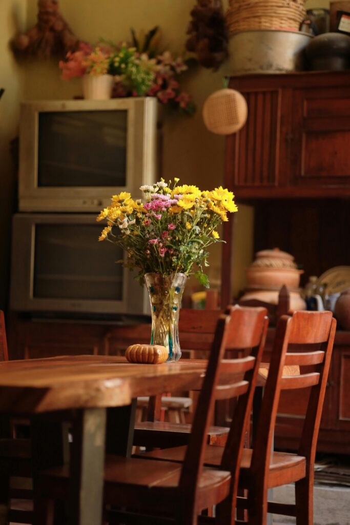 Rustic kitchen featuring vintage decor, wooden table, and flowers in a vase.