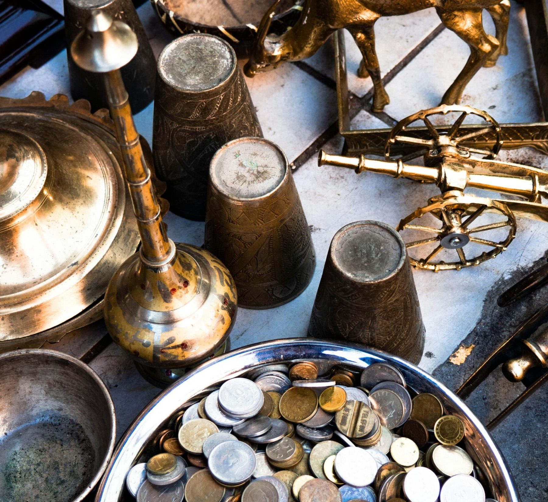 A collection of vintage brass items and coins arranged in a still life composition, showcasing historical artifacts.